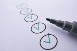 Close-up of a checklist with green checkmarks on white paper using a marker.
