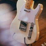 A detailed view of a vintage electric guitar resting on a wooden floor, showcasing classic design.